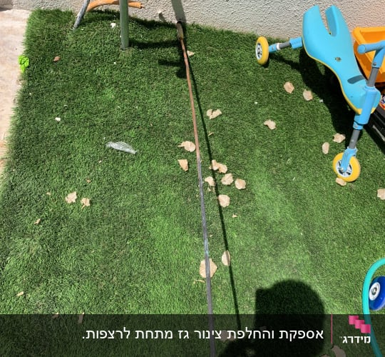 צינור גז על דשא סינתטי ליד קיר